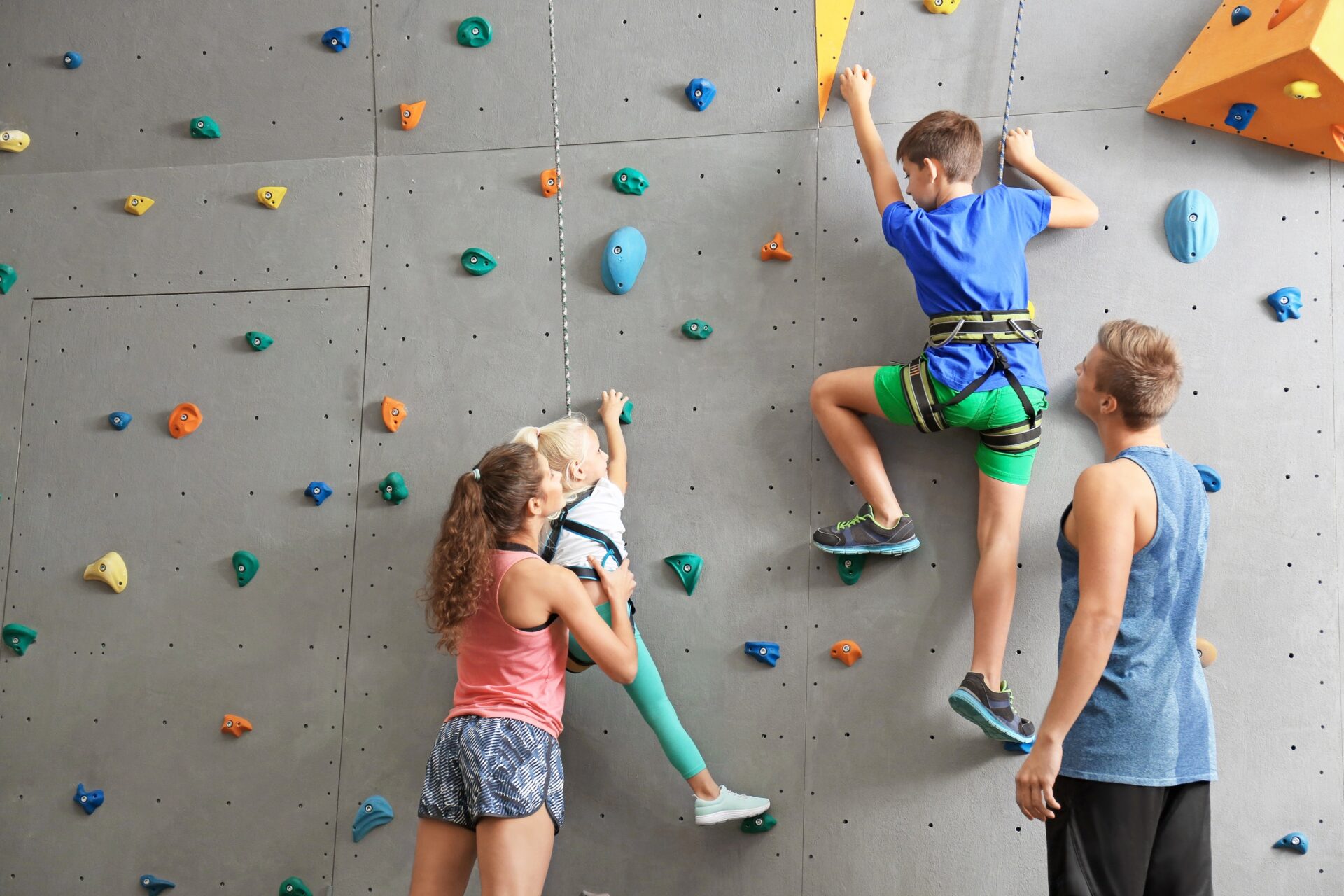 Instructors,helping,children,climb,wall,in,gym
